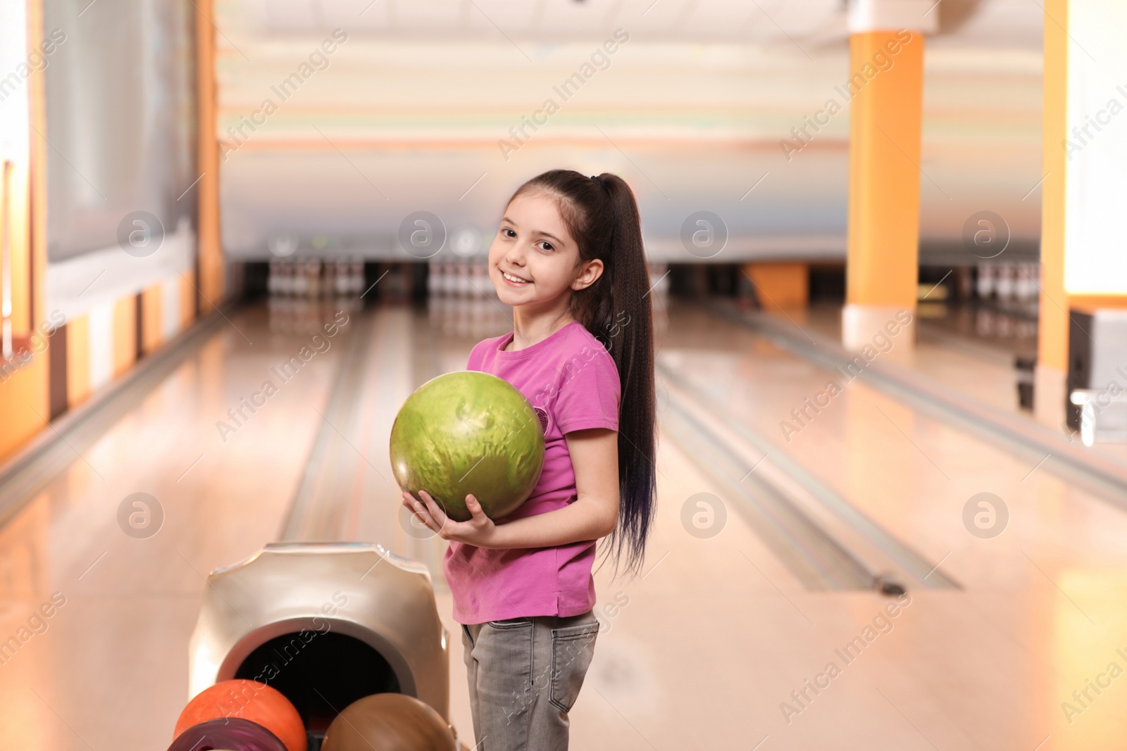 Photo of Little girl with ball in bowling club