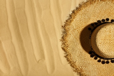 Photo of Straw hat on beach sand, top view. Space for text