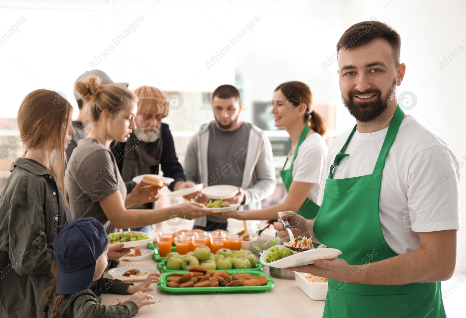 Photo of Volunteer with colleague giving food to poor people indoors