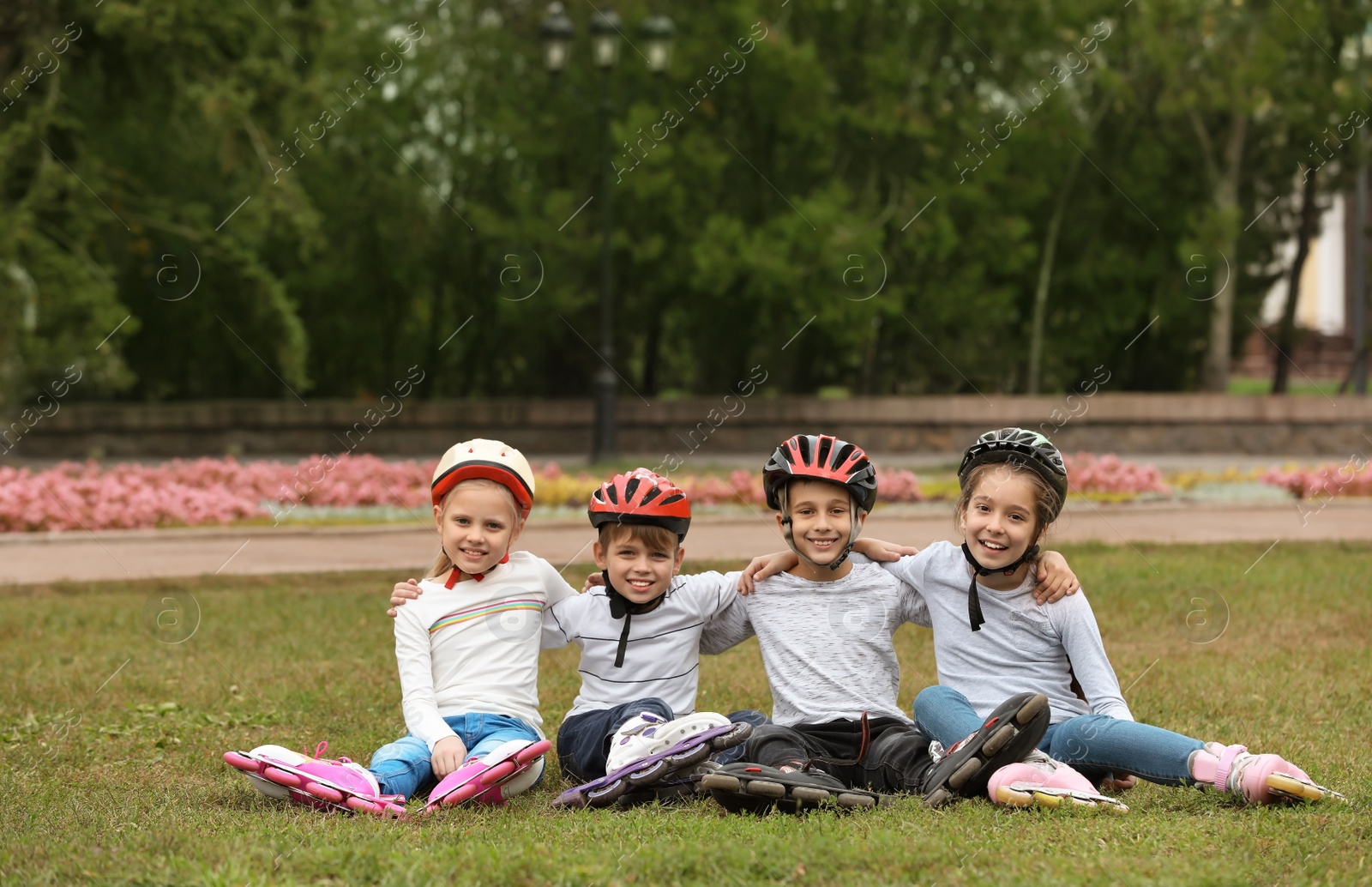 Photo of Little roller skaters sitting on grass in park