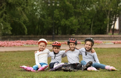 Photo of Little roller skaters sitting on grass in park