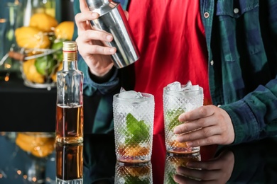 Photo of Bartender preparing delicious mint julep cocktail at table