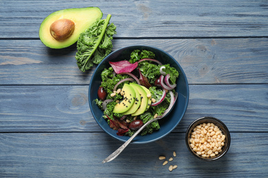 Photo of Tasty fresh kale salad on blue wooden table, flat lay