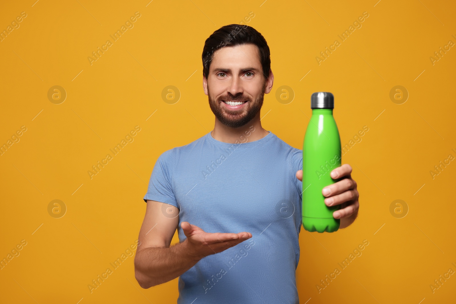 Photo of Man with green thermo bottle on orange background