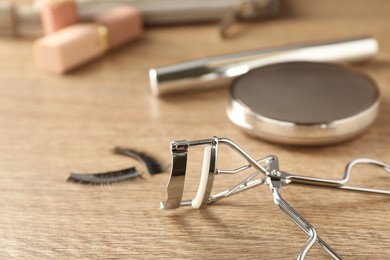 Eyelash curler on wooden table, closeup. Space for text