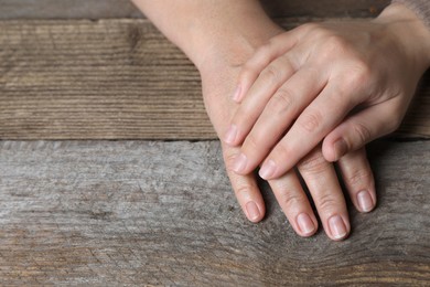 Photo of Woman holding hands with her mother at wooden table, closeup. Space for text