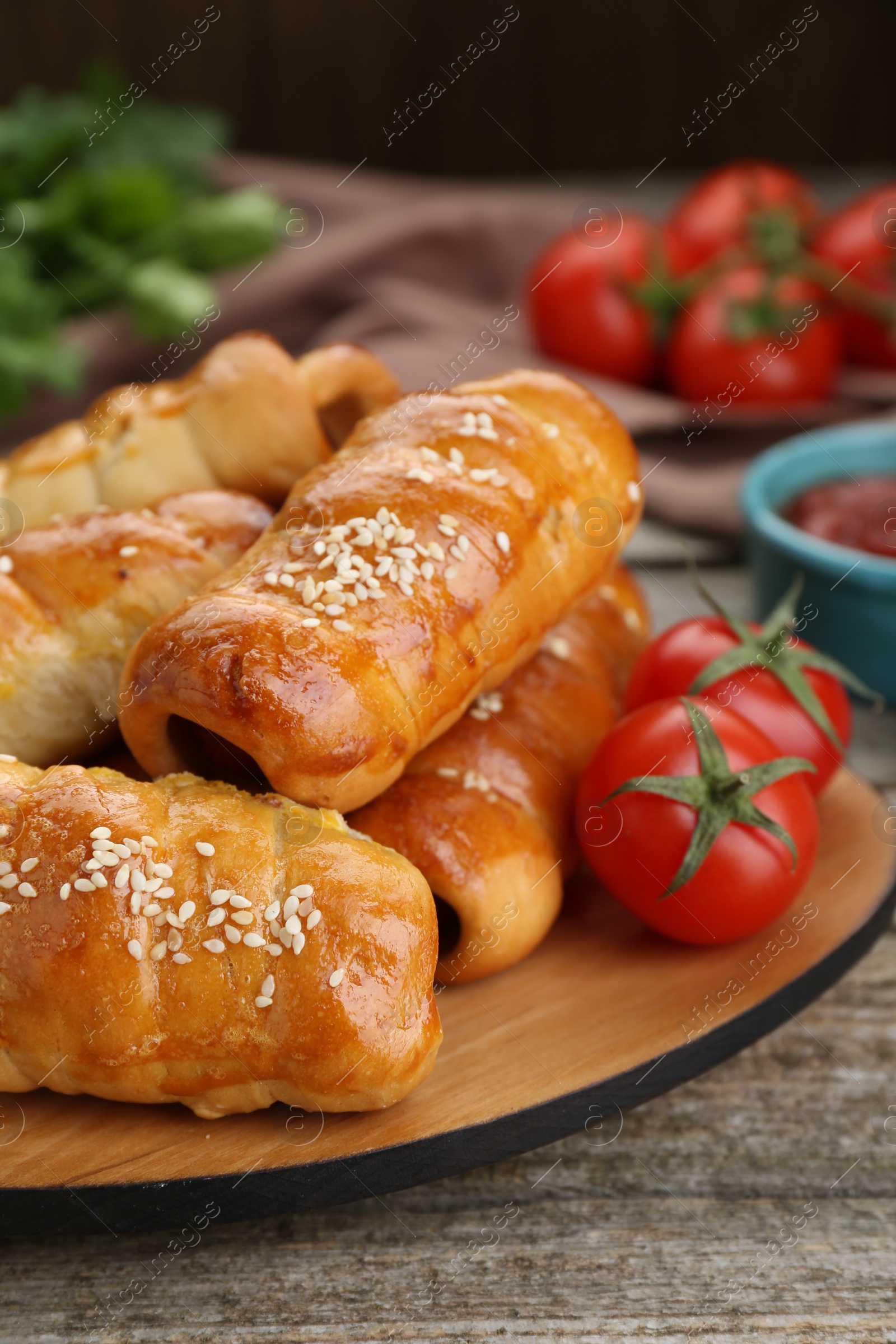 Photo of Delicious sausage rolls and ingredients on wooden table, closeup