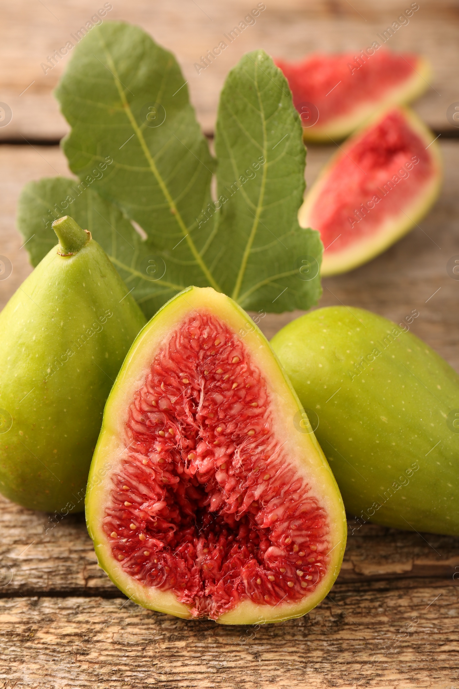 Photo of Half of green fig and fresh fruits on wooden table, closeup