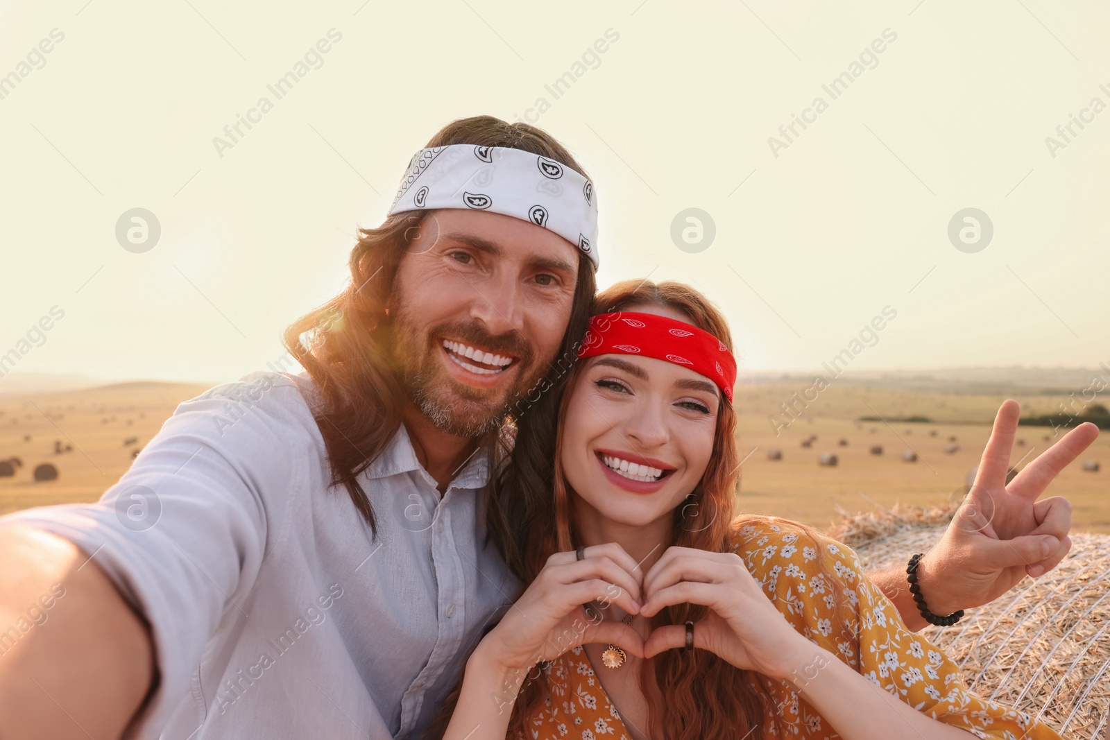 Photo of Happy hippie couple taking selfie in field
