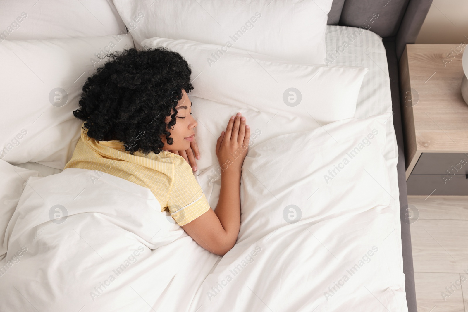 Photo of Beautiful young woman sleeping in soft bed at home, above view