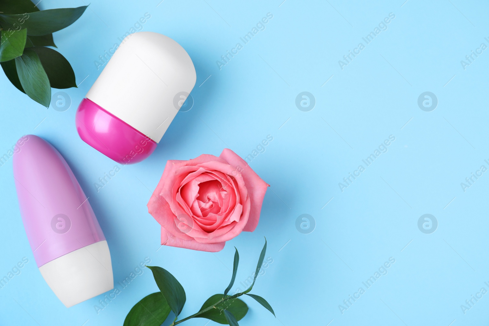 Photo of Flat lay composition with natural female roll-on deodorants on light blue background, space for text
