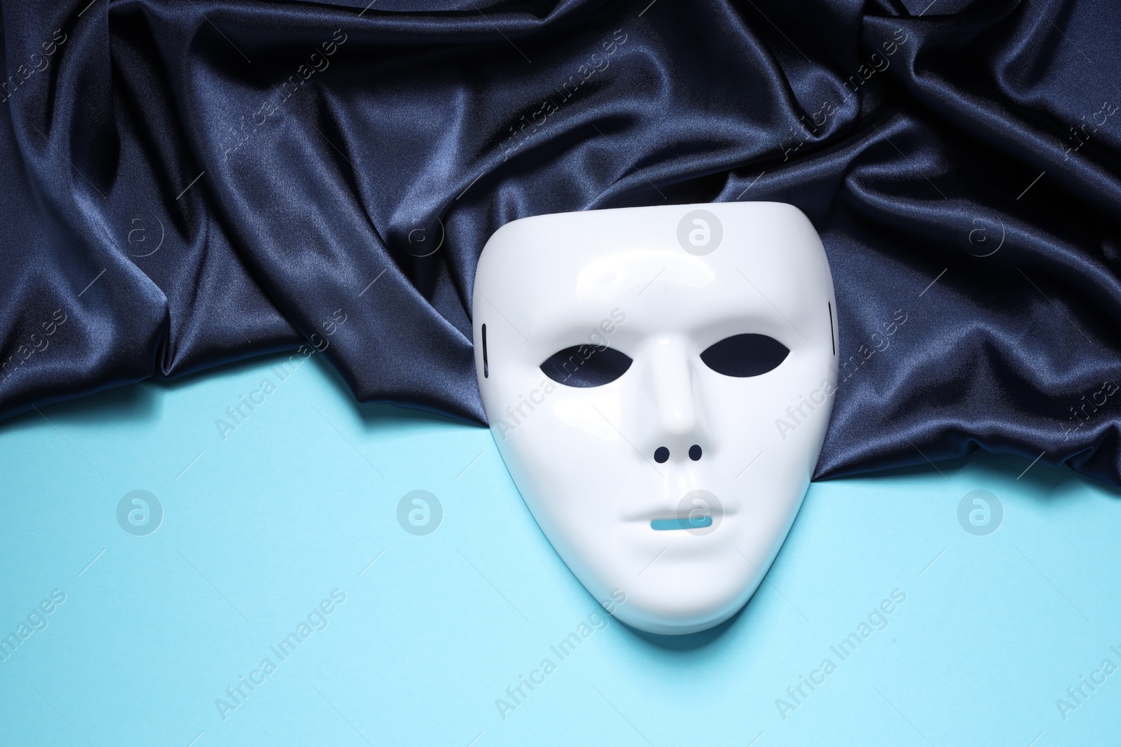 Photo of Theater arts. White mask and fabric on light blue background, top view