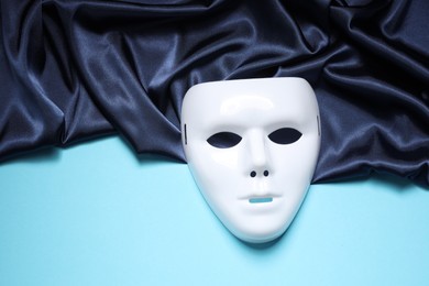 Photo of Theater arts. White mask and fabric on light blue background, top view