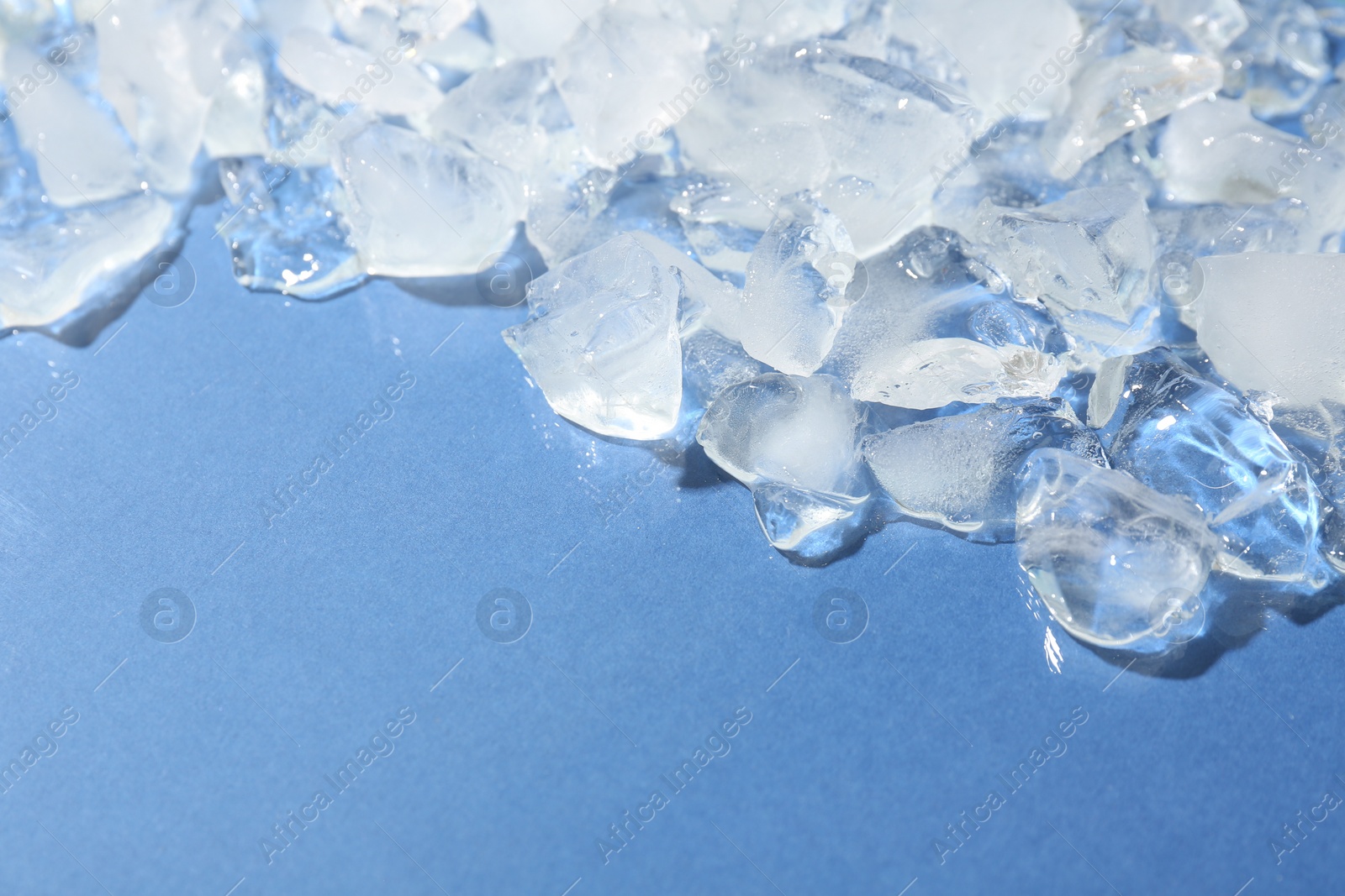 Photo of Pieces of crushed ice on light blue background, above view. Space for text