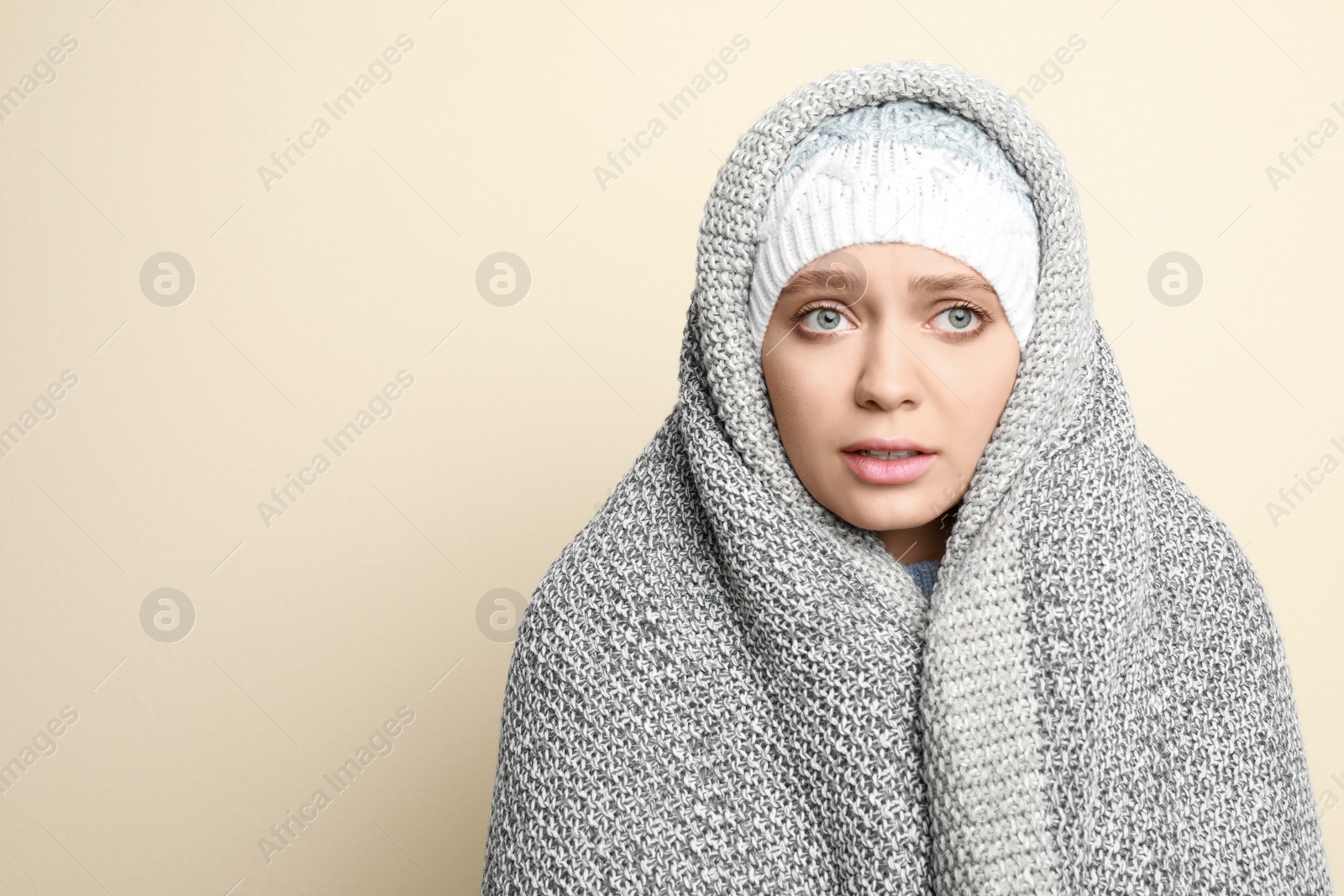 Image of Young woman wrapped in blanket suffering from fever on light background, space for text. Cold symptoms