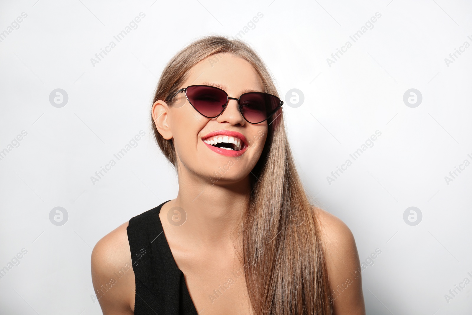 Photo of Young woman wearing stylish sunglasses on light background