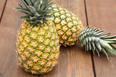 Photo of Delicious ripe pineapples on wooden table. Exotic fruit