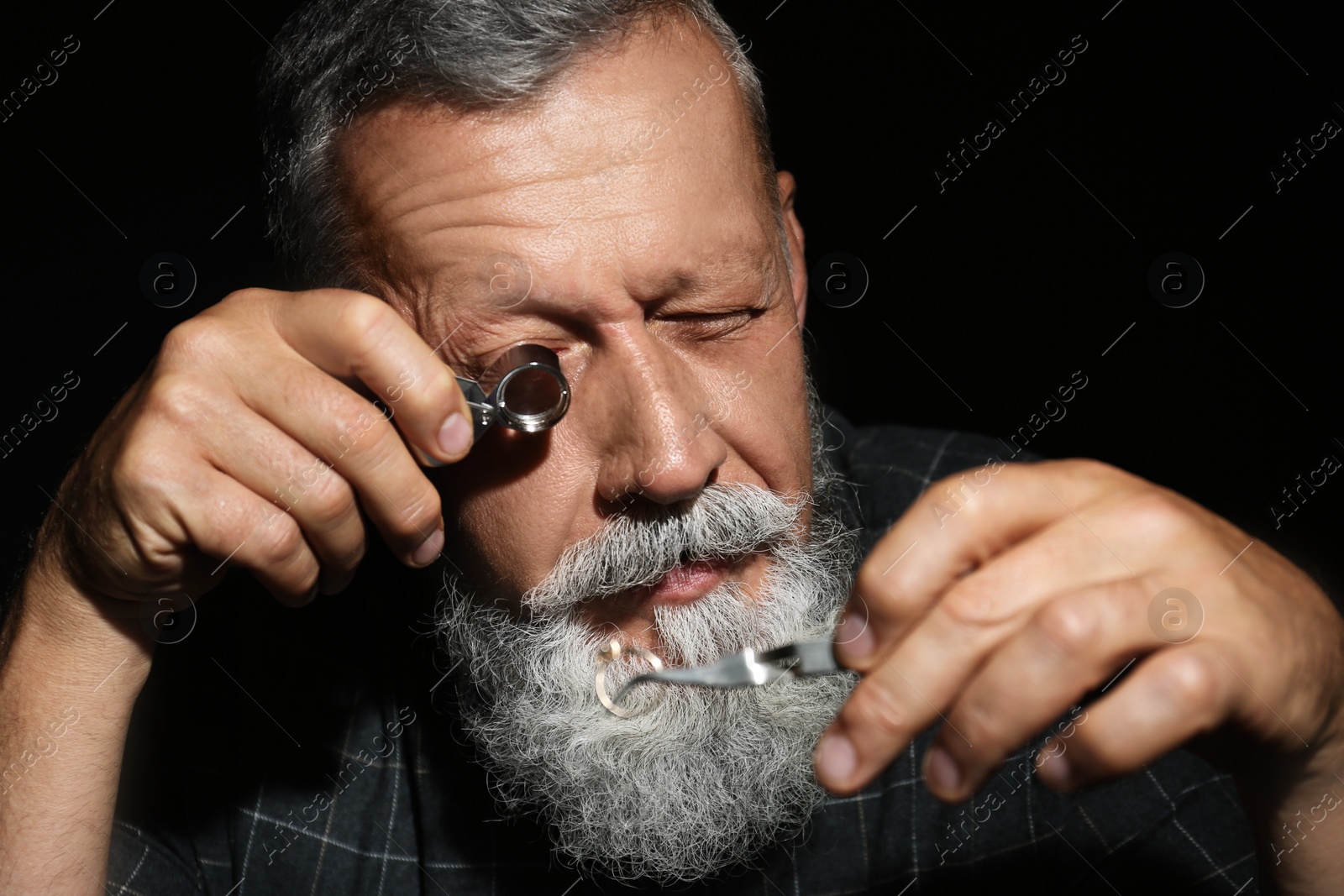 Photo of Male jeweler evaluating diamond ring in workshop, closeup view