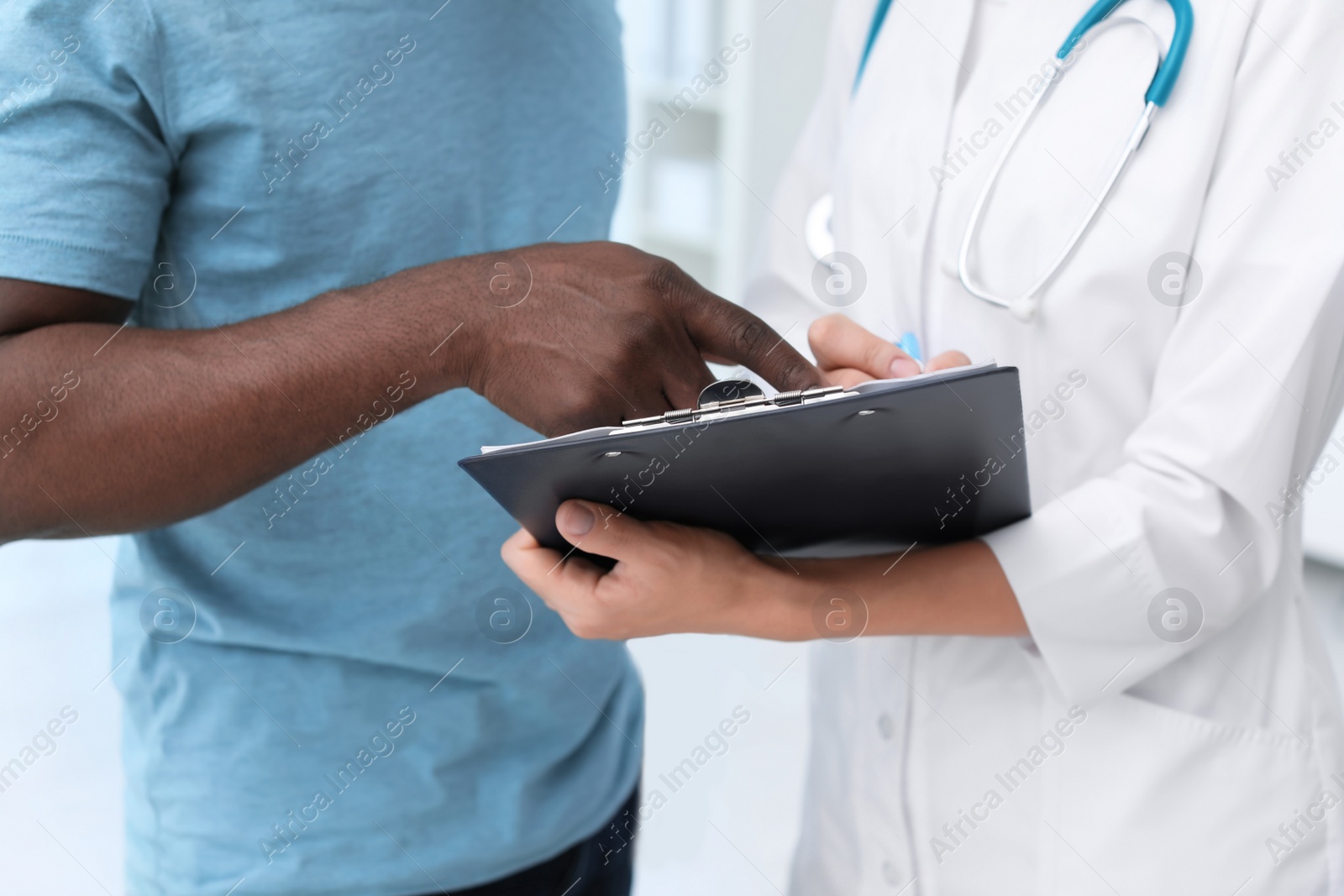 Photo of Young doctor consulting African-American patient in hospital