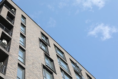 Photo of Modern building with big windows against blue sky outdoors, low angle view. Space for text