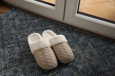 Pair of beautiful soft slippers on mat in room