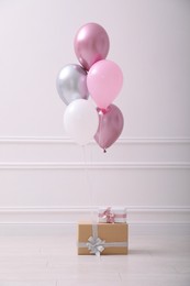 Photo of Two gift boxes and balloons near white wall in room