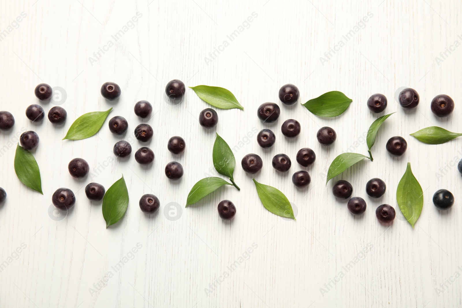 Photo of Flat lay composition with fresh acai berries and leaves on wooden background