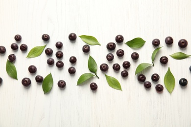 Photo of Flat lay composition with fresh acai berries and leaves on wooden background