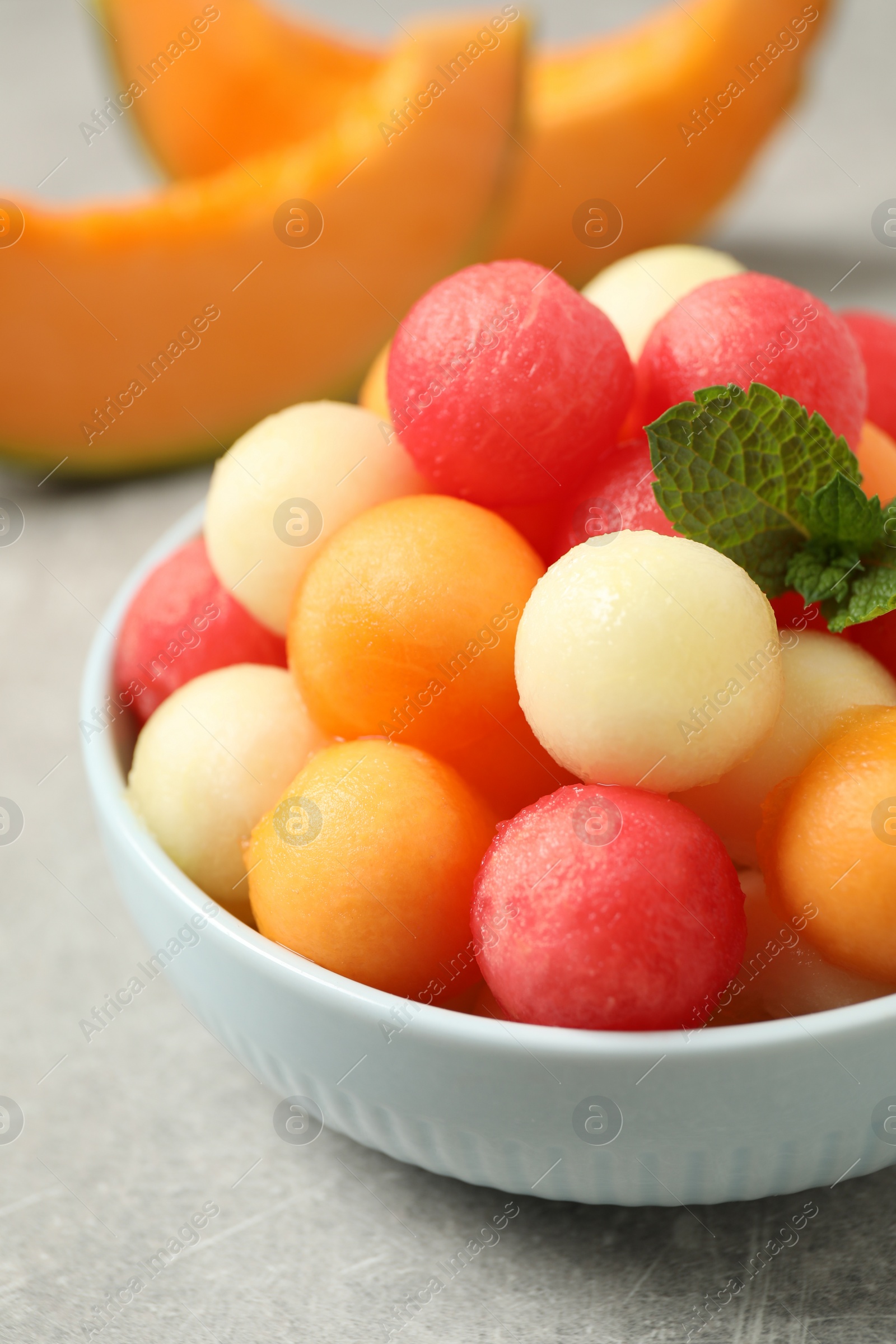 Photo of Melon balls and mint in bowl on grey table, closeup