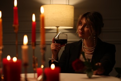 Photo of Beautiful young woman with glass of wine at table in restaurant