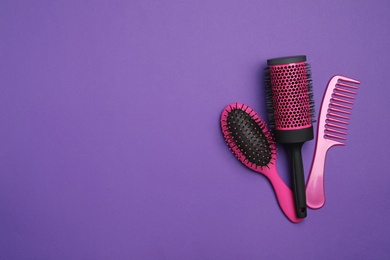 Photo of Modern hair comb and brushes on purple background, flat lay. Space for text