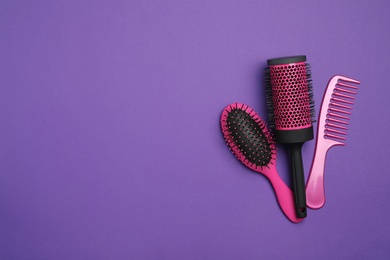 Modern hair comb and brushes on purple background, flat lay. Space for text