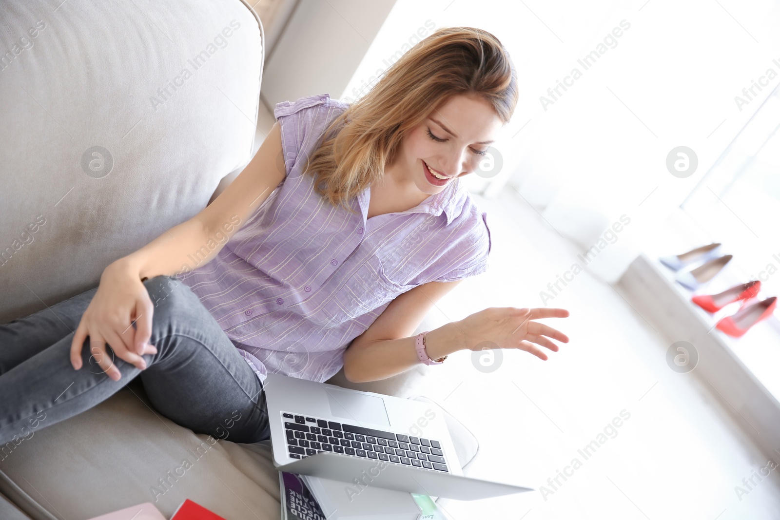 Photo of Young blogger with laptop sitting on sofa at home