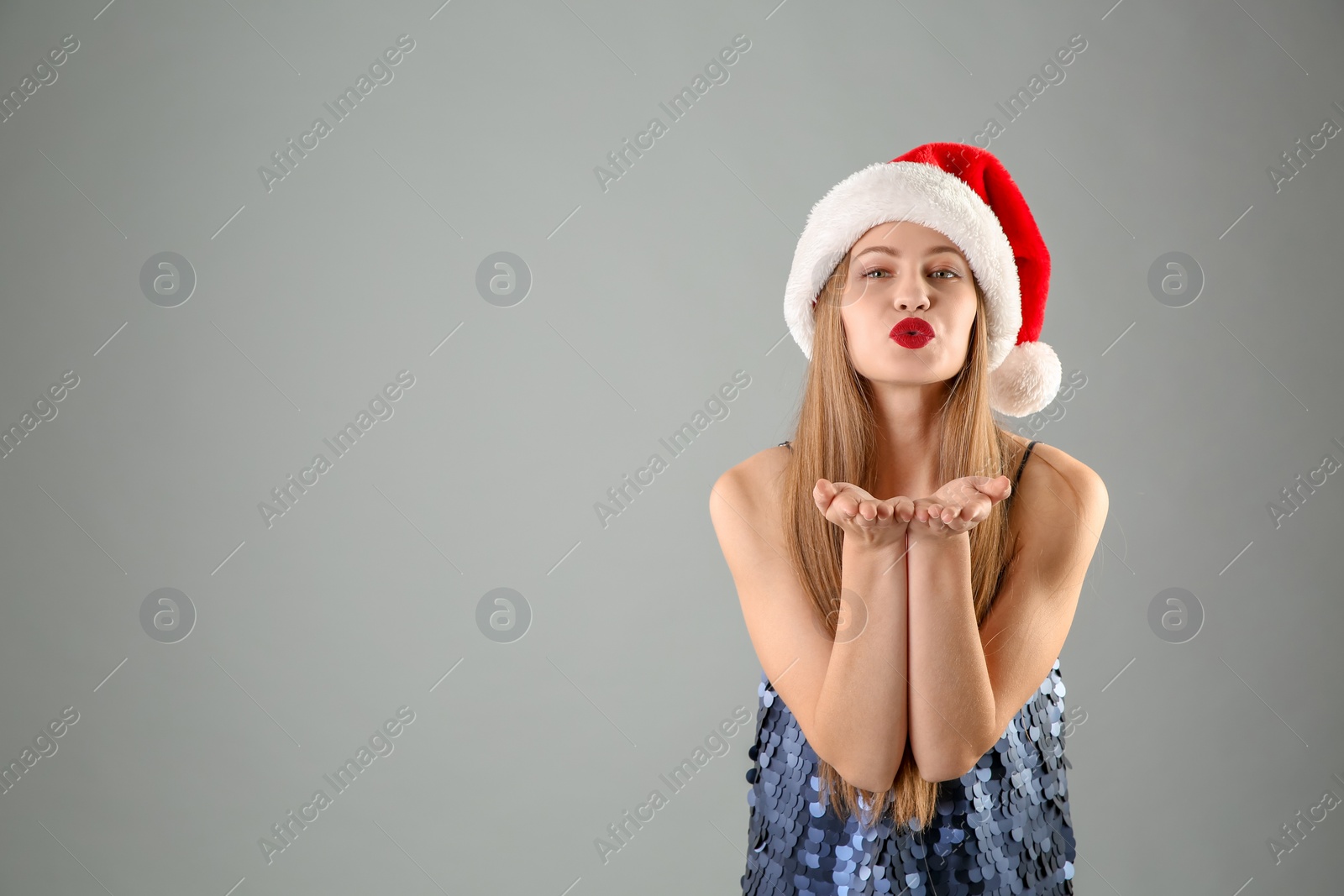 Photo of Young beautiful woman in Santa hat on grey background. Christmas celebration