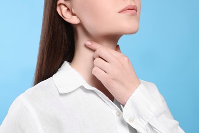 Photo of Woman with sore throat on light blue background, closeup