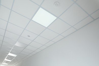 Photo of White ceiling with modern lighting in room, low angle view