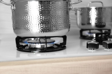 Shiny steel saucepans on modern gas stove, closeup