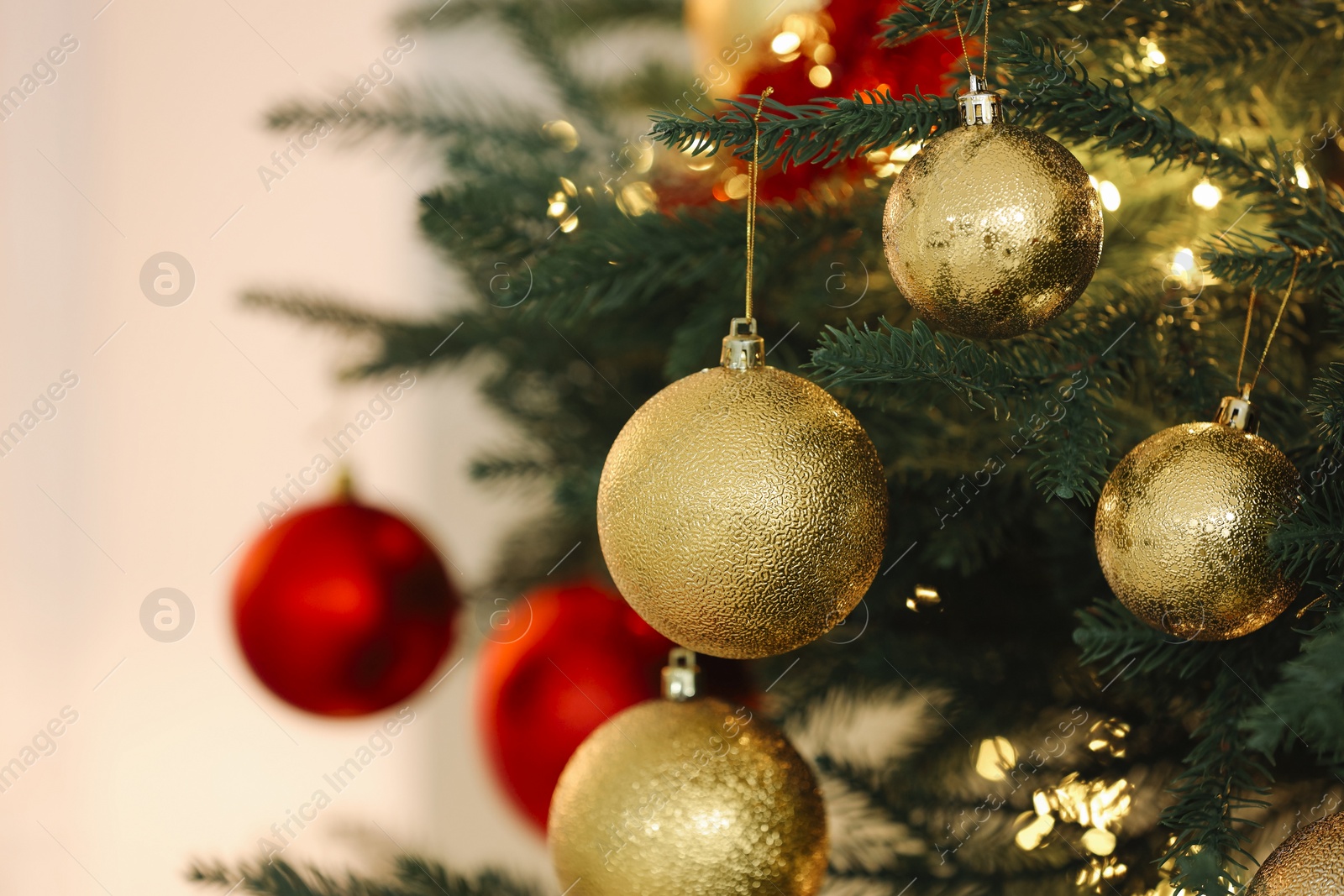 Photo of Christmas tree decorated with festive balls on light background, closeup