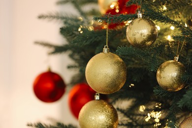 Photo of Christmas tree decorated with festive balls on light background, closeup