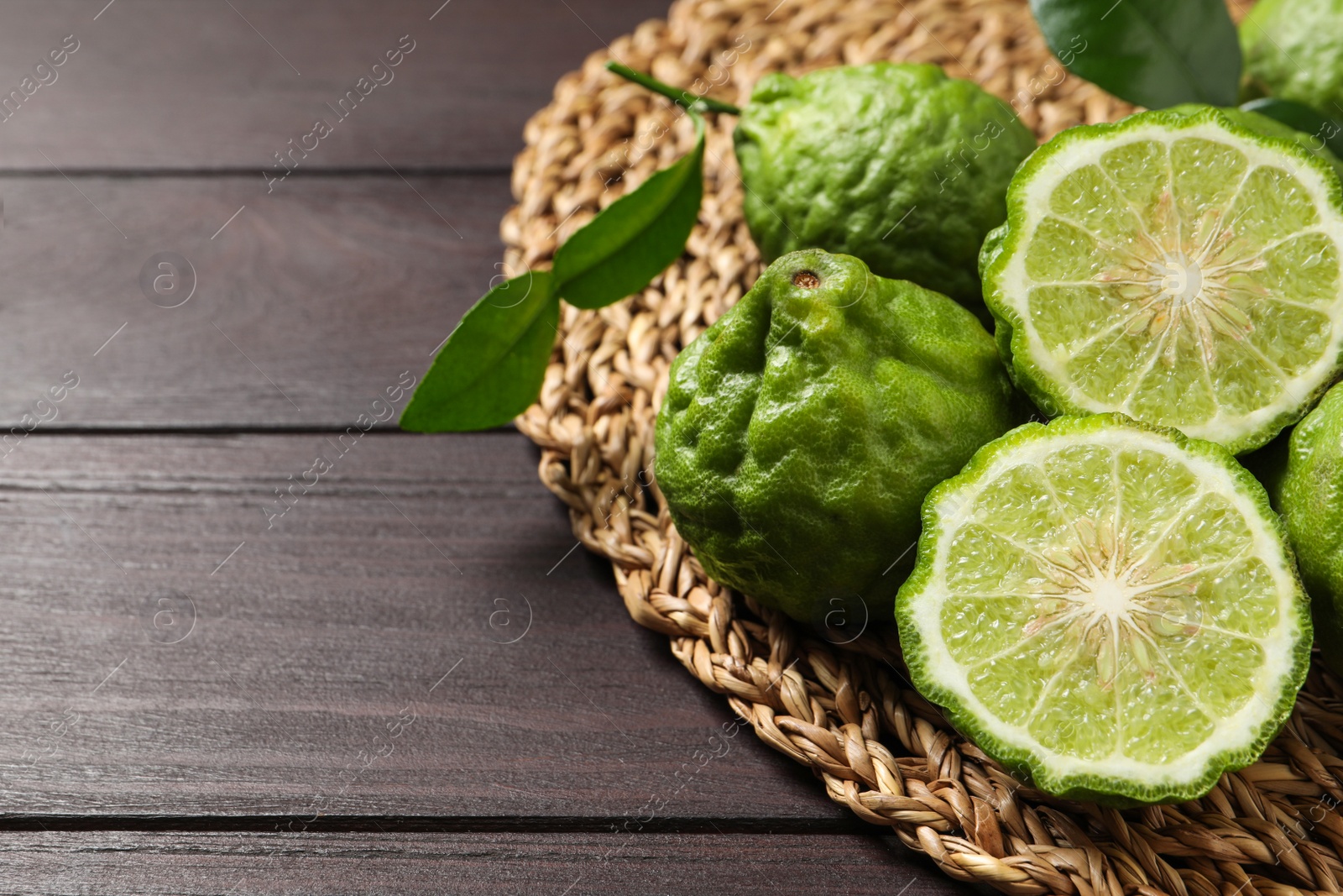 Photo of Whole and cut ripe bergamot fruits on wooden table. Space for text