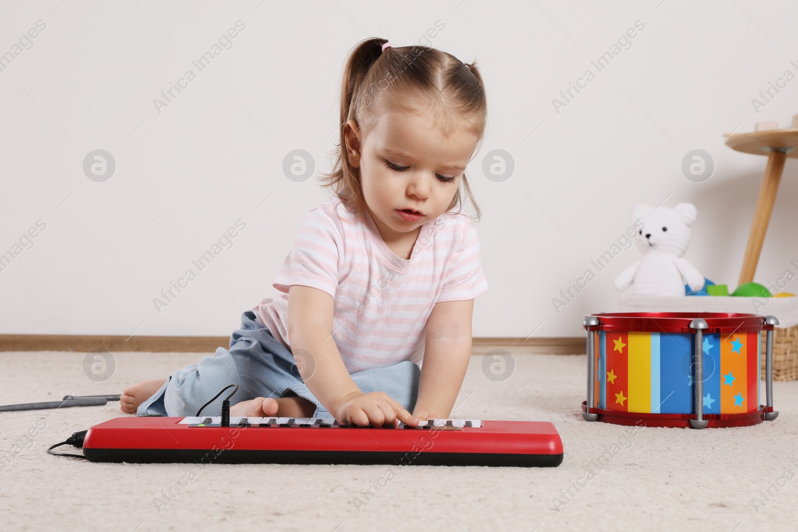 Photo of Cute little girl playing with toy piano at home