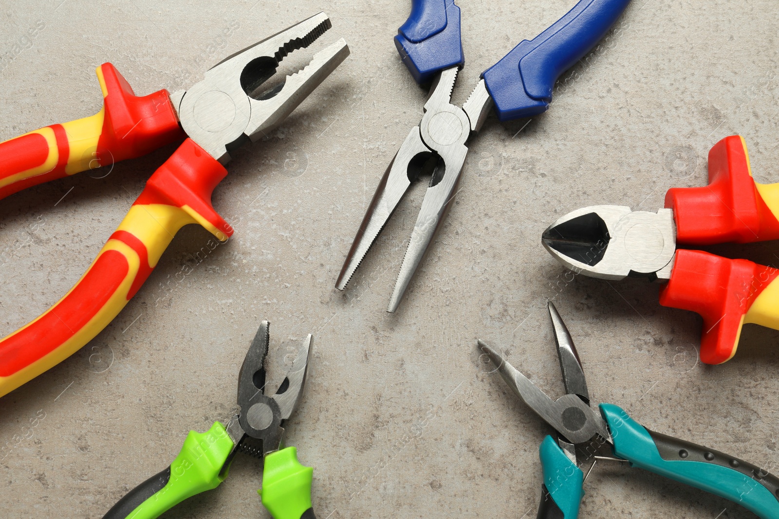 Photo of Different pliers on grey textured table, flat lay