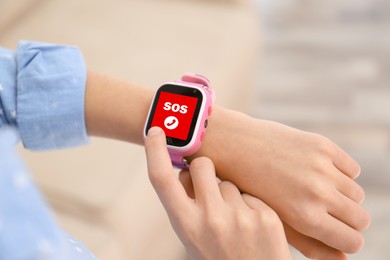 Image of Little girl using SOS function on smartwatch indoors, closeup