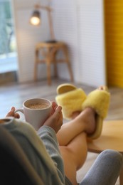 Woman with cup of aromatic coffee relaxing at home, closeup