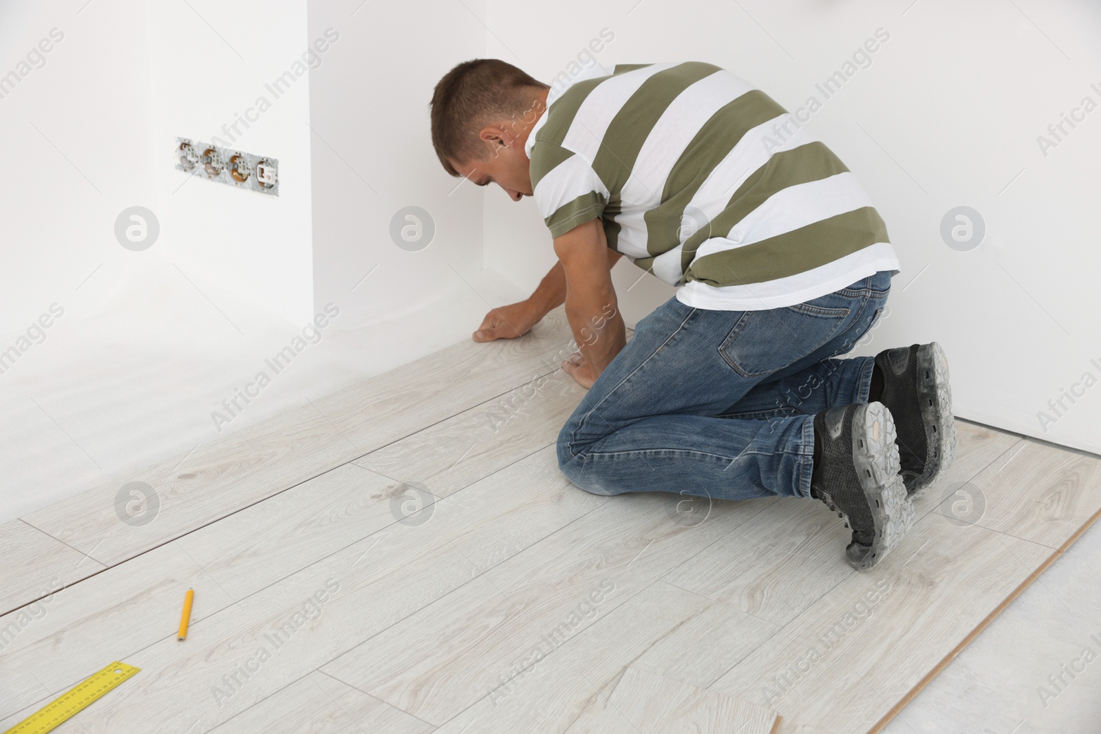 Photo of Professional worker installing new laminate flooring indoors