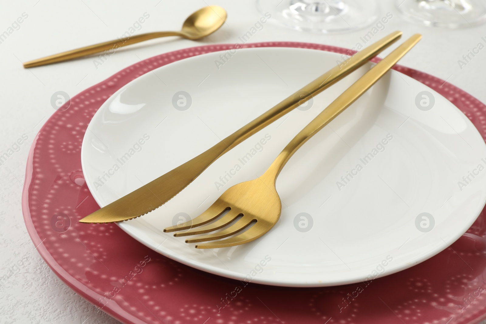 Photo of Stylish setting with cutlery and plates on white textured table, closeup