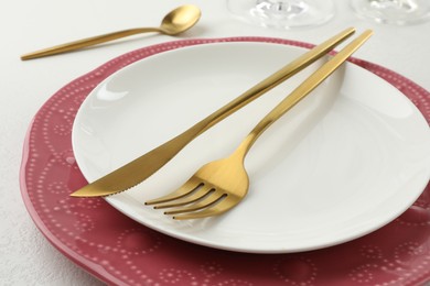 Photo of Stylish setting with cutlery and plates on white textured table, closeup