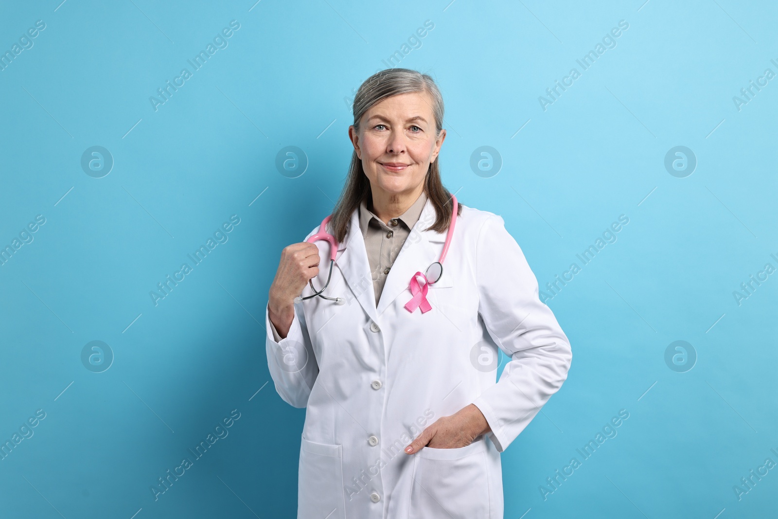 Photo of Mammologist with pink ribbon on light blue background. Breast cancer awareness