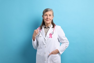 Mammologist with pink ribbon on light blue background. Breast cancer awareness