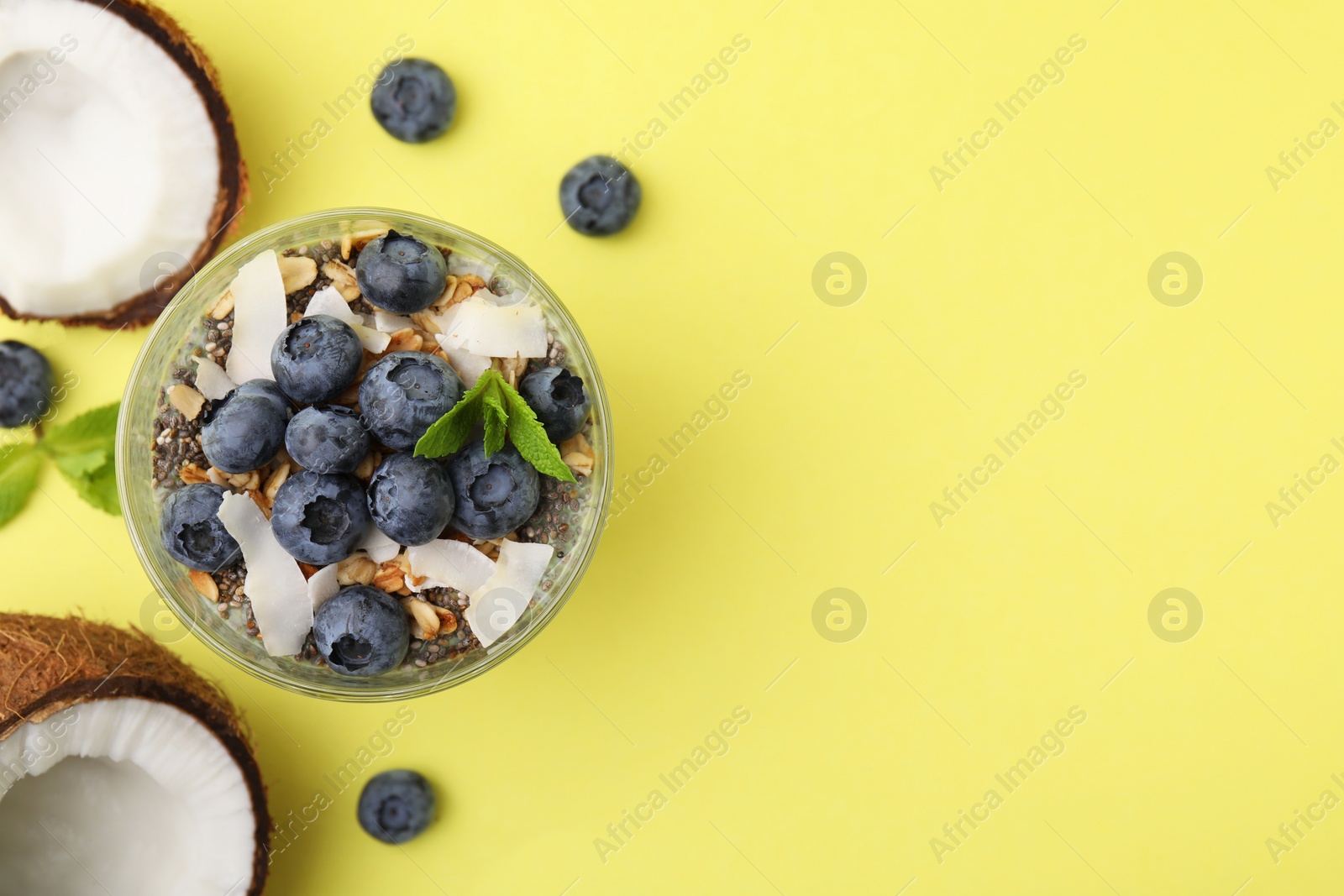 Photo of Tasty smoothie with blueberries, coconut and mint on yellow background, flat lay. Space for text. Healthy breakfast